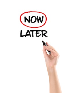 Hand circling "now" instead of "later" on a white board